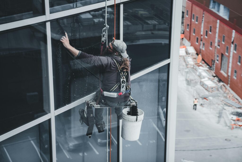 pexels photo 17041923 17041923 A worker cleaning skyscraper windows with a harness in an urban setting.